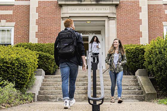 Photo of three Chatham University students walking on Shadyside Campus in front of a red brick building